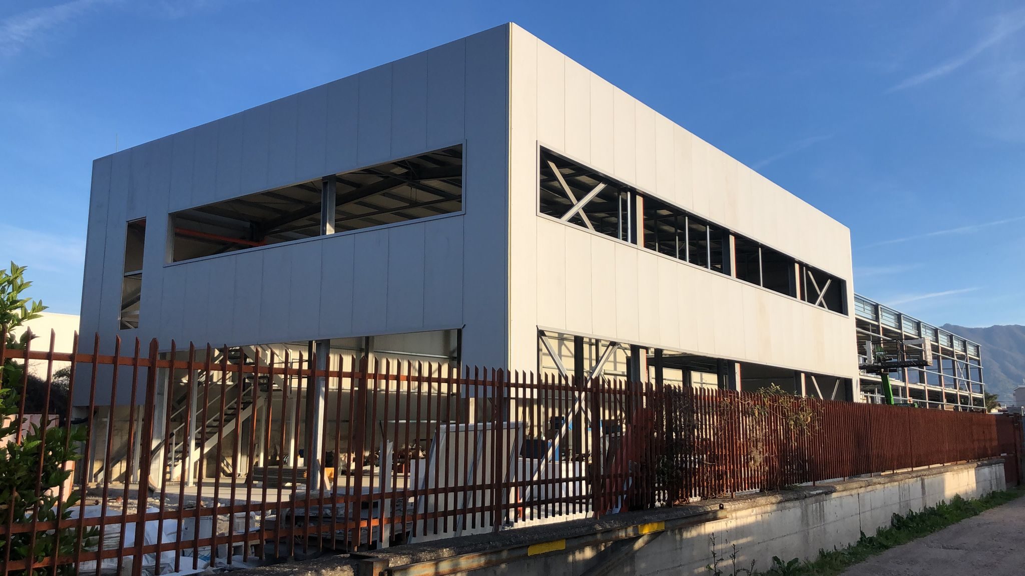 Edificio industriale a due livelli con rivestimento in pannelli metallici chiari e grandi aperture vetrate