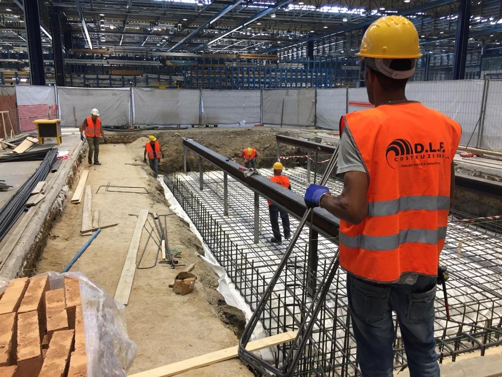 Squadra D.L.F. al lavoro sulle armature di fondazione all'interno di un capannone